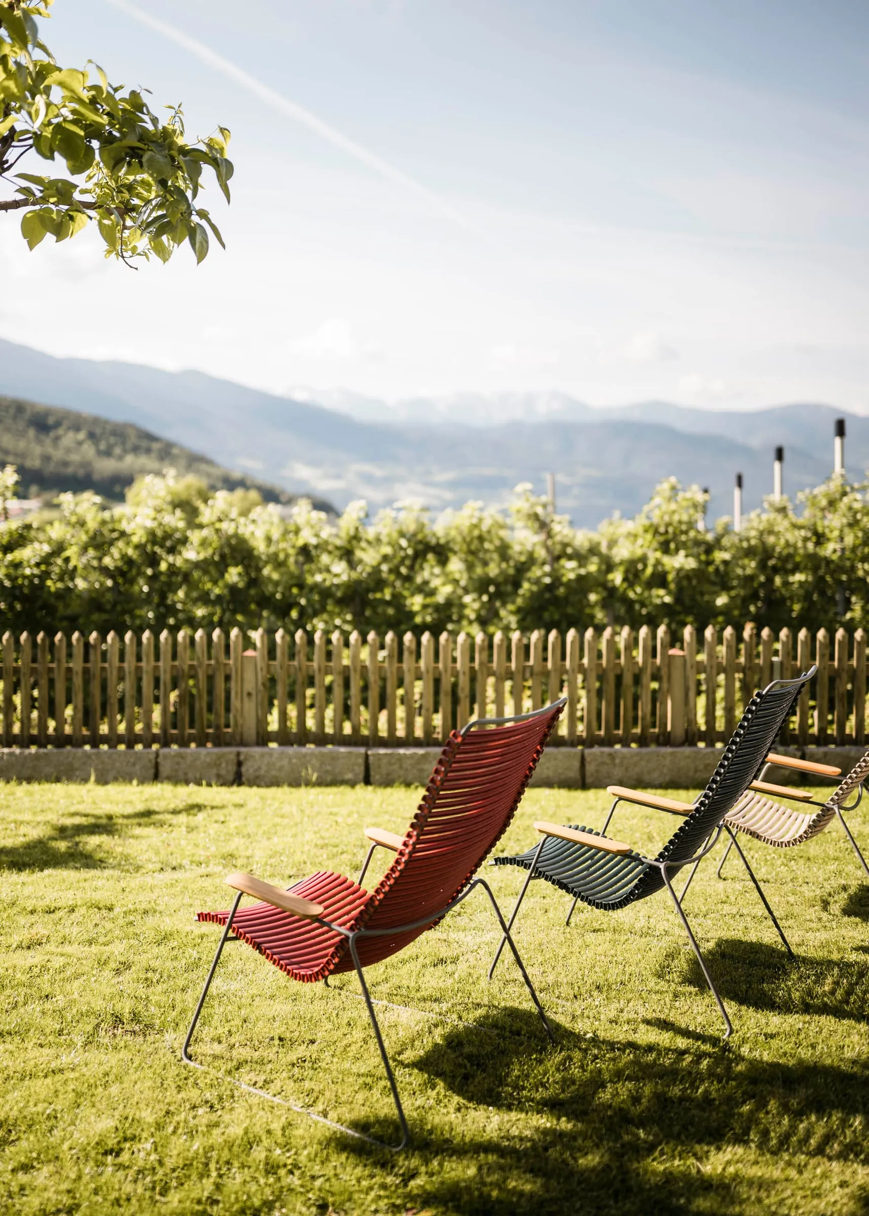 Ligstoelen in de tuin met uitzicht over de appelboomgaarden naar de bergen